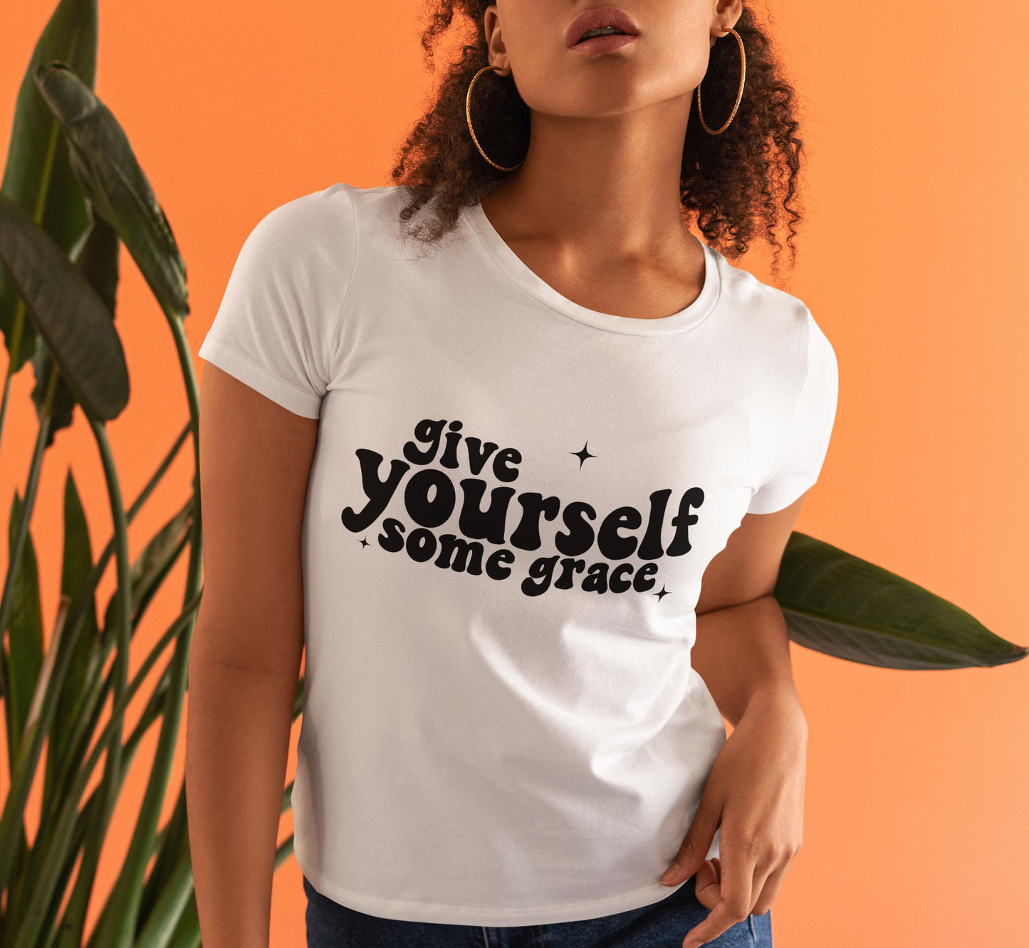 Woman in a white shirt with "give yourself some grace" written in black letters.
