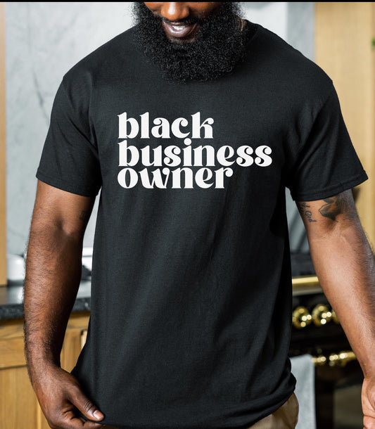 Smiling Black man in a black t-shirt that says Black Business Owner in white letters