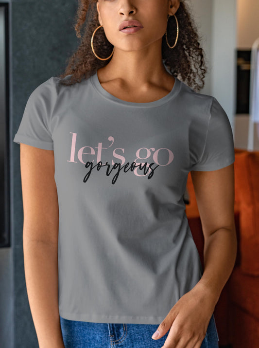 woman in a grey shirt that says "lets go gorgeous" in pink and black letters